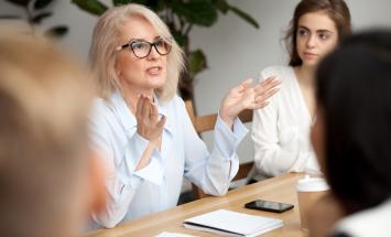 Person gesticulating with their hands at a table filled with people