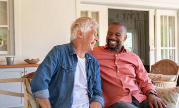 Two people on a porch looking at each other and smiling 