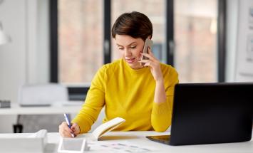 Person on the phone writing in a notebook