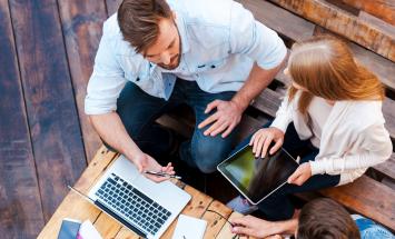 people around a table with laptops and tablets