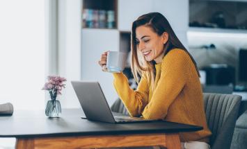 person holding a cup of coffee at the computer