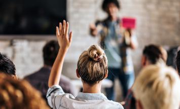 Woman raising her hand to ask a question